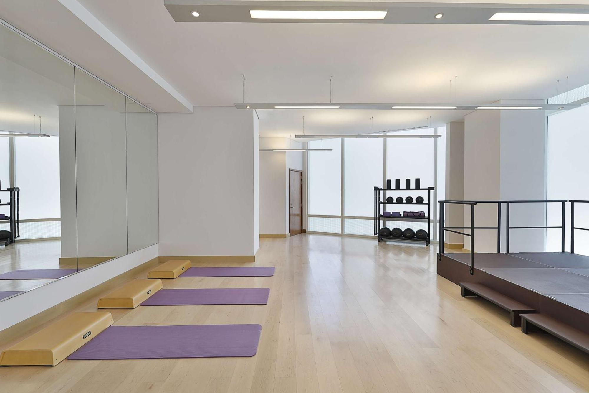 Hilton Riyadh Hotel & Residences Eksteriør bilde The photo depicts a spacious exercise or workout studio. It features wooden flooring and a large mirror on one wall. There are three purple yoga mats neatly placed on the floor, and a small set of wooden steps beside them. In the background, there is