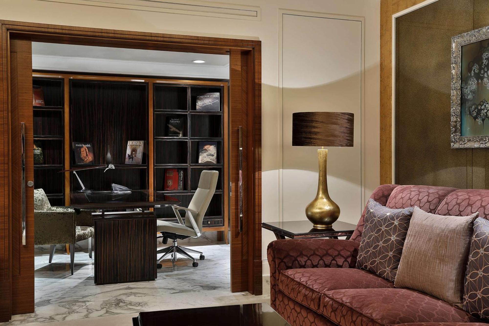 Hilton Riyadh Hotel & Residences Eksteriør bilde The photo shows a stylish and modern interior space that appears to be a home office or study. In the foreground, there is a comfortable burgundy sofa with decorative pillows. Behind the sofa, there is a doorway leading to the office area, which incl