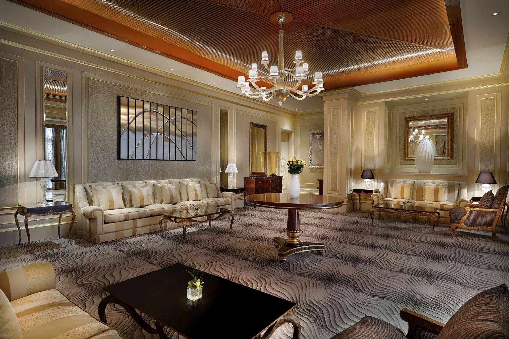 Hilton Riyadh Hotel & Residences Eksteriør bilde The photo depicts an elegant and well-appointed living room or lounge area. It features a soft color palette with beige and cream tones throughout. 

1. **Furniture**: There are two plush sofas, a round wooden coffee table in the center, and a couple