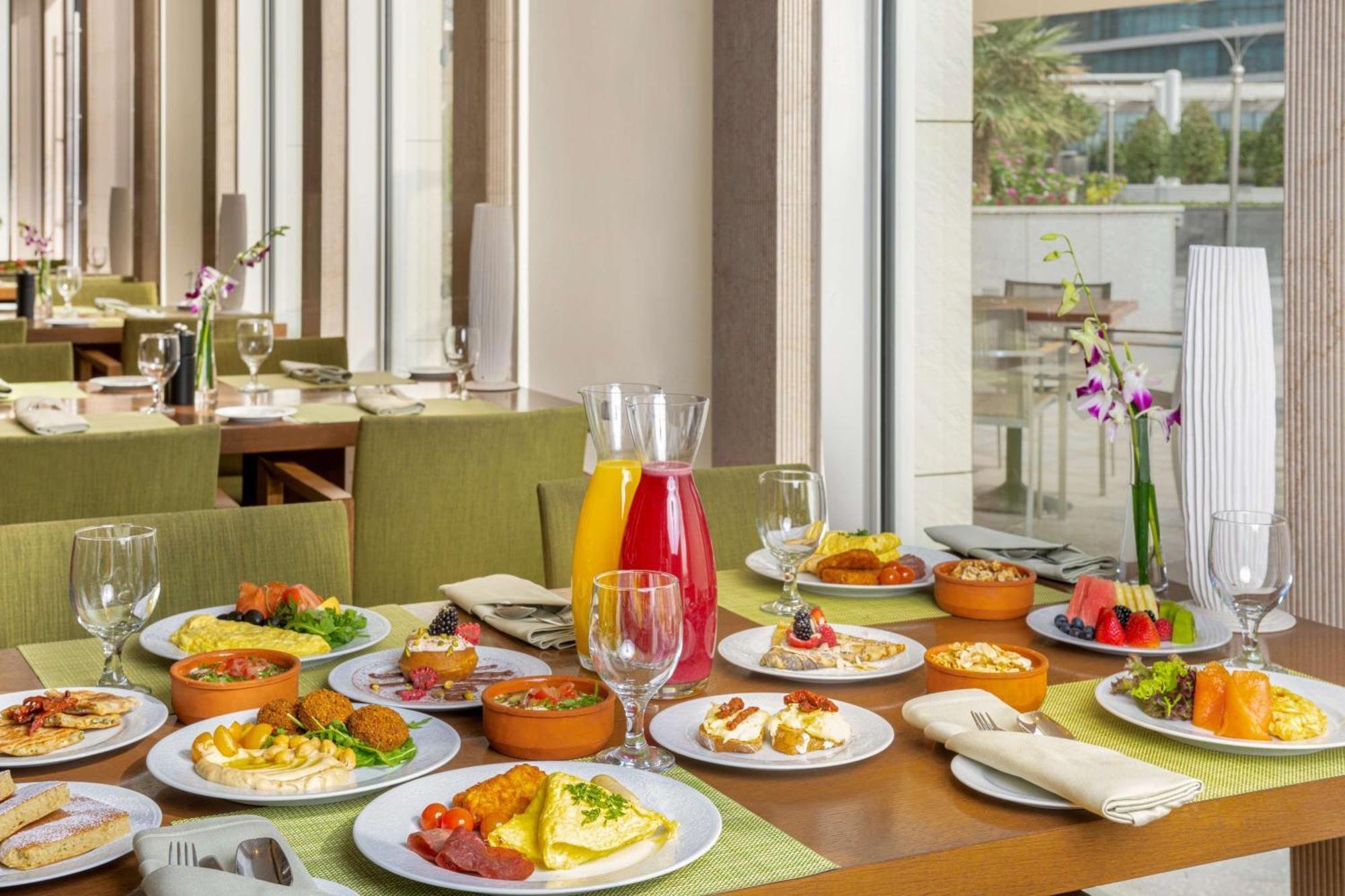 Hilton Riyadh Hotel & Residences Eksteriør bilde The photo showcases a beautifully arranged dining table filled with a variety of dishes. There are multiple plates featuring an assortment of foods, including salads, appetizers, and main courses, presented in a vibrant and appetizing manner. Additio